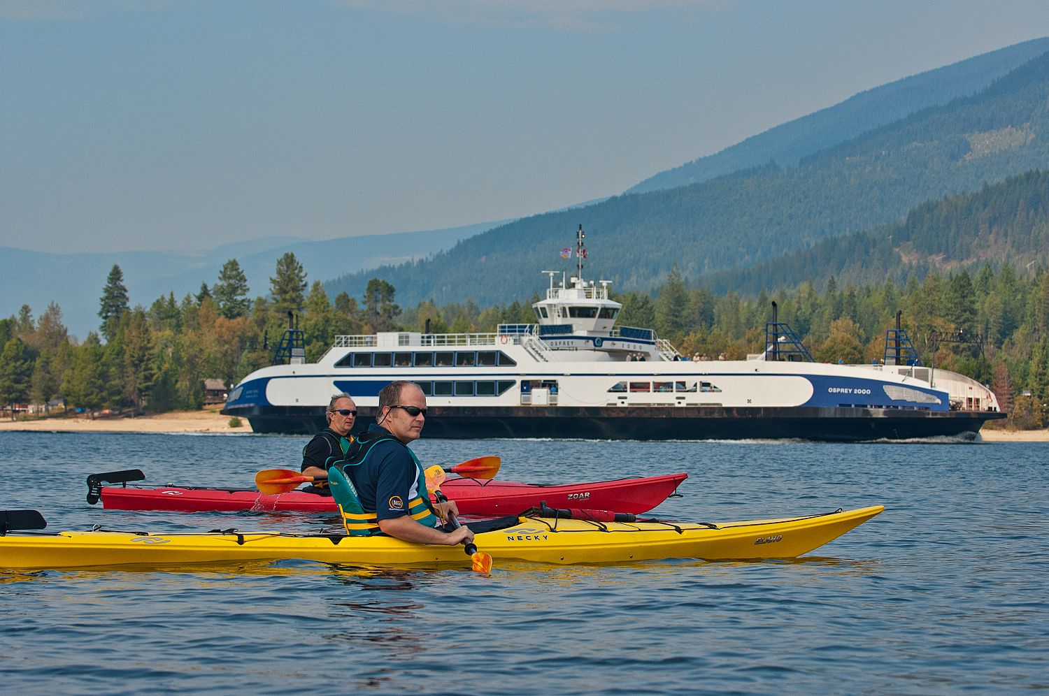 Photo by David Gluns of people kayaking in front of the Kootenay Lake ferry